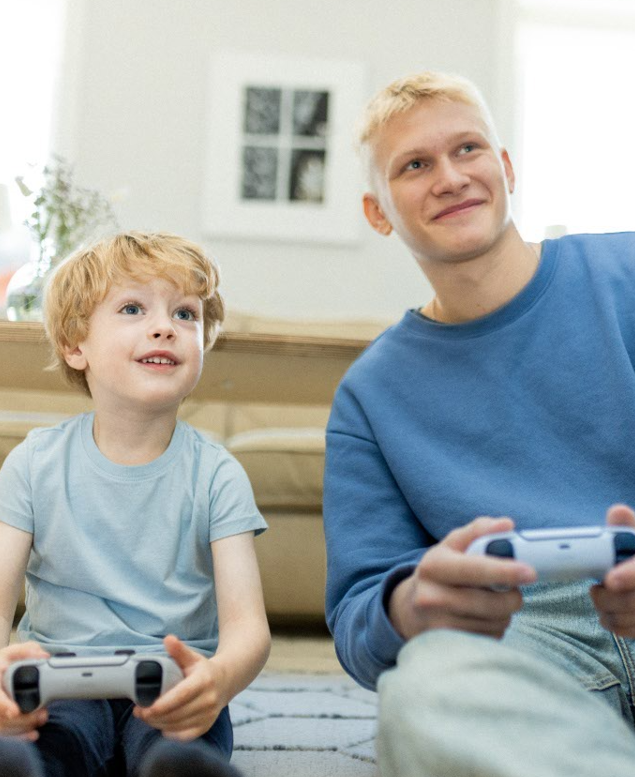 Ung man och pojke sitter på golvet och spelar TV-spel