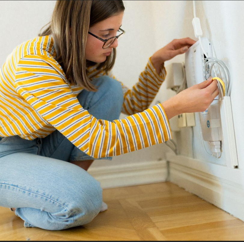 Flicka sitter på huk och fixar med en router